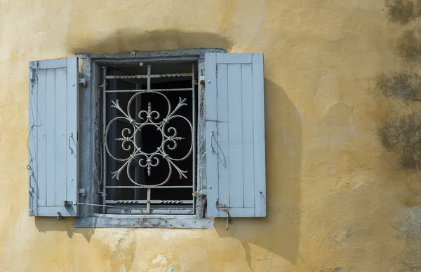 Blue iron window on a worn stucco wall. — Stock Photo, Image