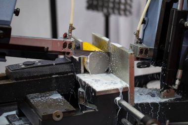 Bant testeresi metal çubukları keser ve soğutucuyla soğutur. Endüstriyel metal fabrikası