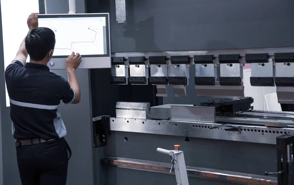 CNC 'yi seçen sanayi teknisyeni hidrolik basınç frenini senkronize ediyor. Metal fabrikası.