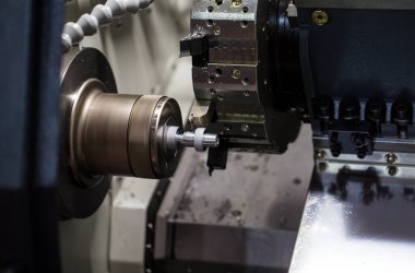 CNC torna ya da dönme makinesi metal parçasının sonundaki ipliği kesiyor. Endüstriyel metal iş makineleri
