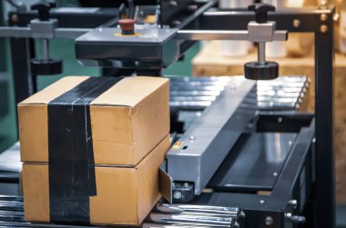 Carton paten taşıyıcısında. Otomatik karton bant kapama makinesi. Endüstriyel lojistik deposu