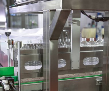 Üretim hattı plastik torbaya koymadan önce üfleme makinesinden boş plastik şişe topluyor.