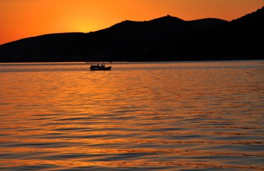 Bir balıkçı teknesi ile deniz üzerinde romantik günbatımı