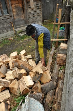 Yaşlı adam kış için odunları düzenlemek
