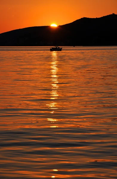 Ρομαντικό ηλιοβασίλεμα πάνω στη θάλασσα με ένα αλιευτικό σκάφος — Φωτογραφία Αρχείου