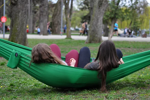 Mladí lidé relaxují v houpací sítě v parku — Stock fotografie