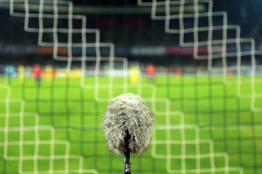 Kalenin arkasında bir futbol sahası üzerinde büyük ve tüylü spor mikrofon