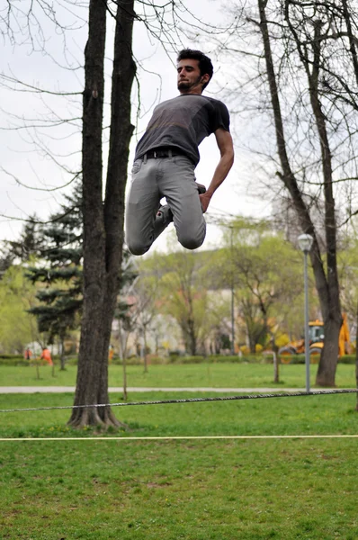 Cara fazendo truques de slackline — Fotografia de Stock