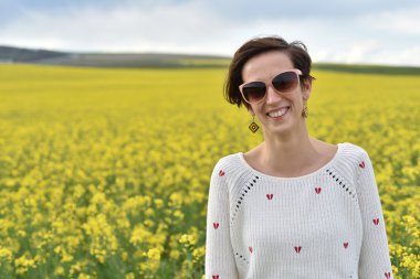 Genç kadın bir kanola tarlanın ortasında mutlu hissediyor