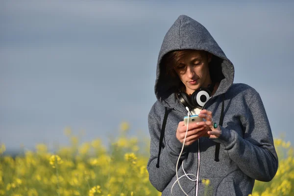 Jovem com capuz enviando uma mensagem em seu telefone inteligente — Fotografia de Stock