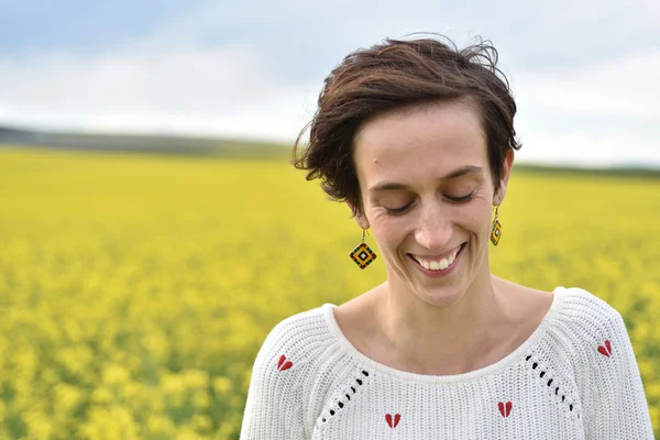Young woman feeling happy in the middle of a canola field — Stock Photo, Image