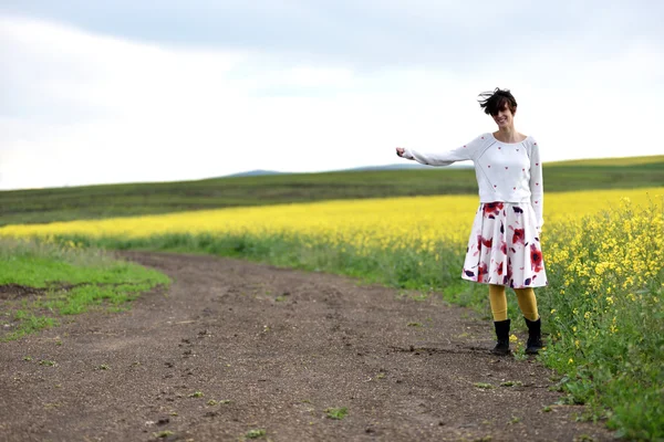 Хипстерская девушка в платье автостопом возле сельской дороги — стоковое фото