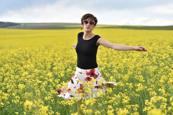 Hipster girl walking through a canola field. Freedom concept — Stock Photo, Image