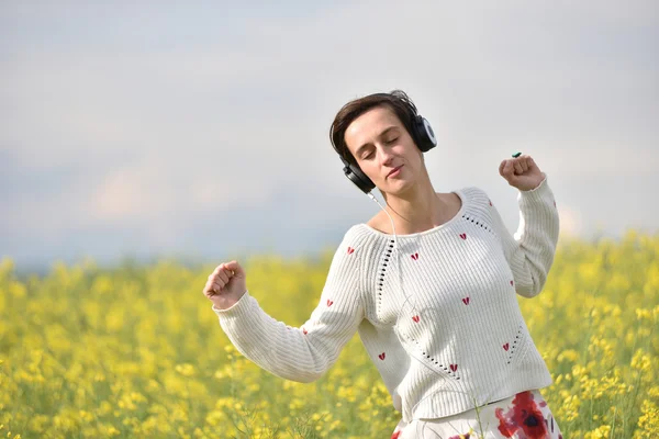 Giovane donna felice ascoltare musica in cuffia all'aperto — Foto Stock