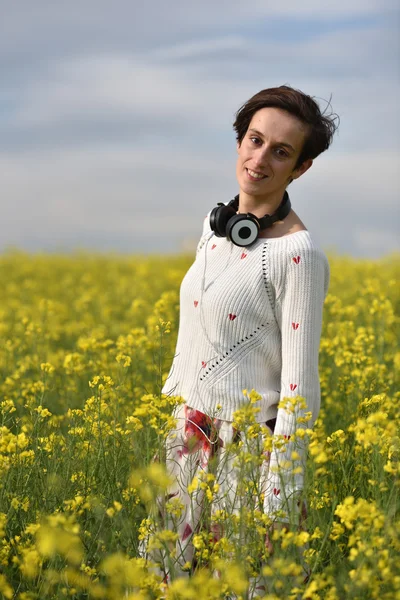 Mujer joven sintiéndose feliz en medio de un campo de canola — Foto de Stock