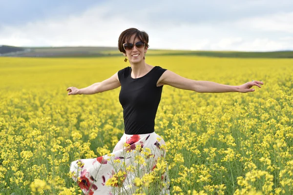 Hipster girl walking through a canola field. Freedom concept — Stock Photo, Image