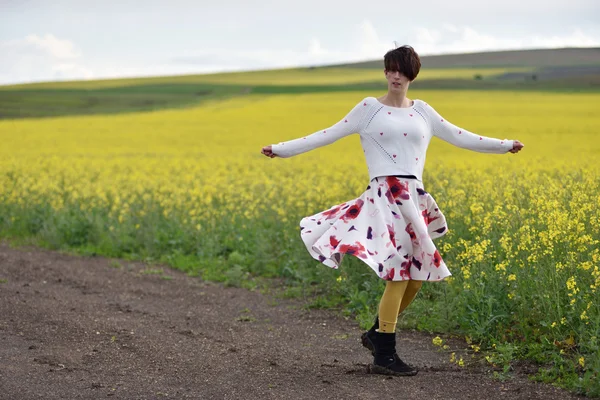 Sexy vrouw in rok dansen in de buurt van een canola-veld — Stockfoto