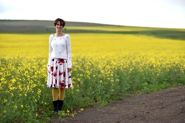 Hipster chica en falda posando cerca de un campo de canola — Foto de Stock