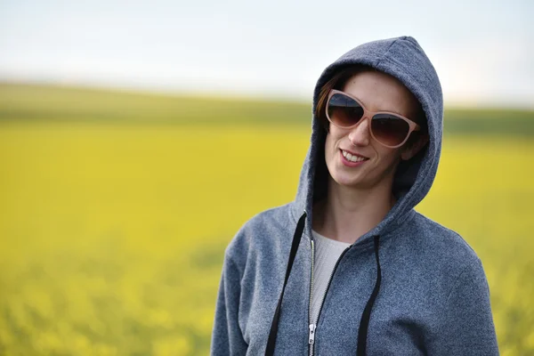 Lachende meisje in hoodie en zonnebril in de buitenlucht — Stockfoto