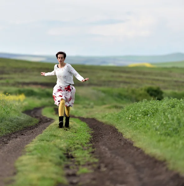 Jonge vrouw draait op een weg van het platteland. Concept van de vrijheid — Stockfoto