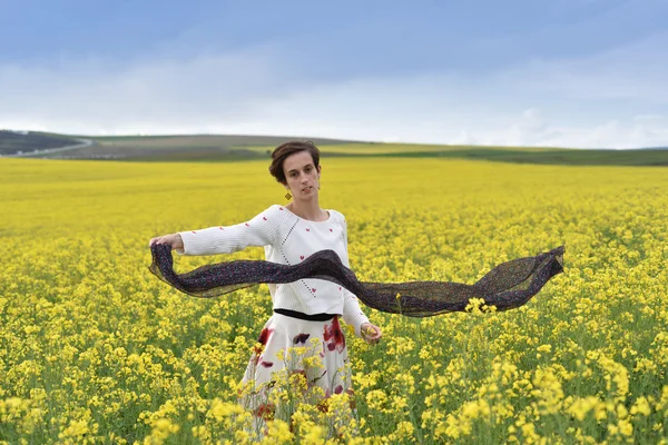 Splendida giovane donna che gioca con la sciarpa in un campo di colza — Foto Stock
