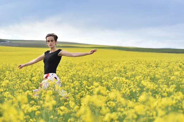 Young woman cheering in canola field in the summer — Stock Photo, Image