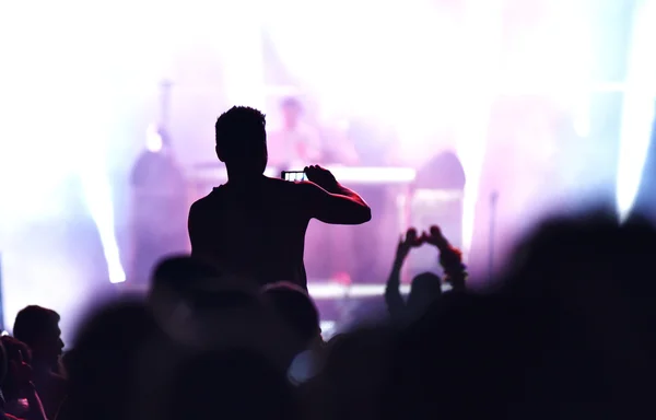 Animando a la multitud frente a las luces del escenario brillantes —  Fotos de Stock