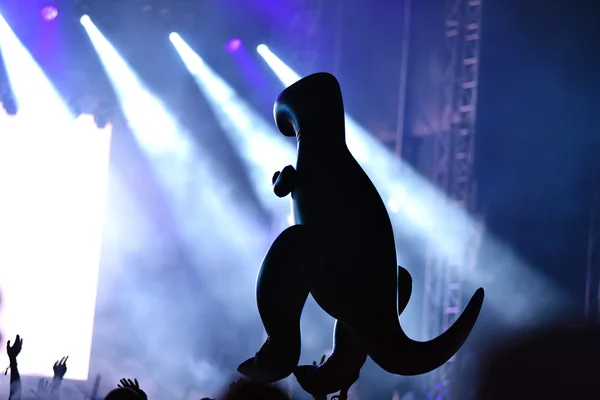 Silhouette of an inflatable dinosaur at a live concert. Stage li — Stock Photo, Image