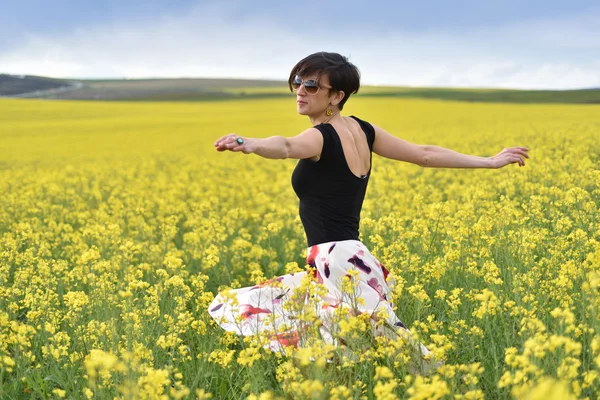 Hermosa mujer animando en campo de colza y disfrutando soleado su — Foto de Stock