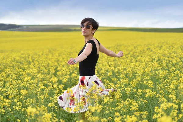 Hermosa mujer animando en campo de colza y disfrutando soleado su —  Fotos de Stock
