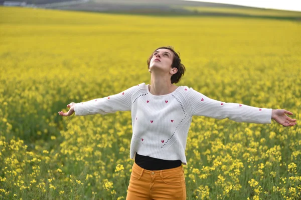 Hermosa mujer animando en campo de colza y disfrutando soleado su —  Fotos de Stock