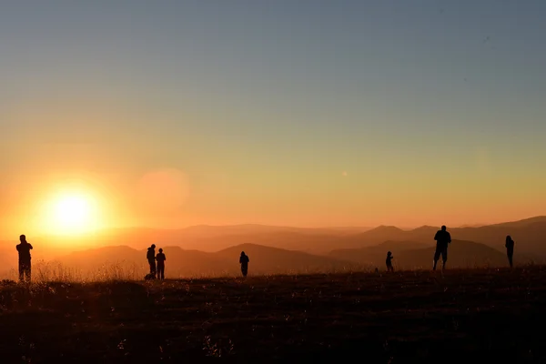 Gente relajándose y disfrutando de la puesta de sol en las montañas — Foto de Stock