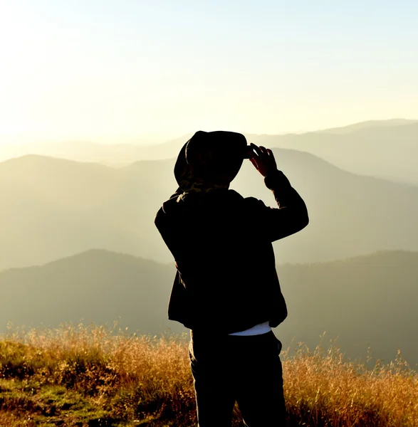 Homem com chapéu fotografando o pôr do sol nas montanhas — Fotografia de Stock