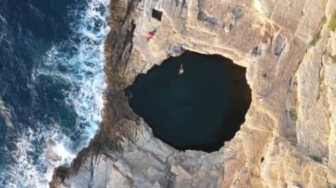 Giola 'daki doğal deniz havuzu, lagün' de suya atlayan bir kadının hava görüntüsü. Thassos Adası, Yunanistan