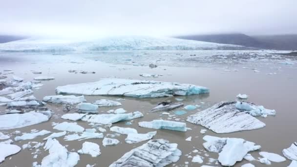 アイスランドのFjallsarlon氷河ラグーンの浮遊氷山の上を飛んでいます 地球温暖化と気候変動による氷冠の融解の空中像 — ストック動画