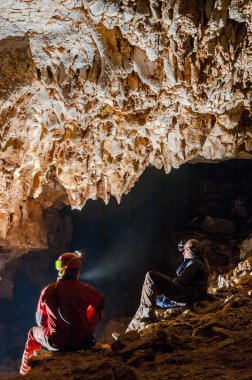 Speleologlar mağaradaki sarkıtları merak ediyor ve hayranlık duyuyorlar. Mağara, keşfedilmemiş yeraltı geçitlerini keşfetmeye adanmış bir bilim ve ekstrem spordur.