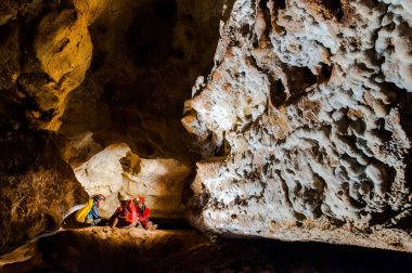 Group of speleologists resting during a cave exploration. Caving is a dangerous extreme sport practiced by professionals clipart