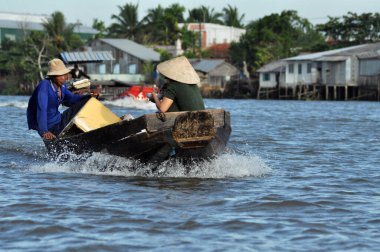 CAI RANG, VİETNAM - 17 Şubat 2013: Mekong deltasındaki ahşap tekneleriyle seyahat eden ve çalışan insanlar sadece tekne ve gemilerde ulaşımın mümkün olduğu yerler