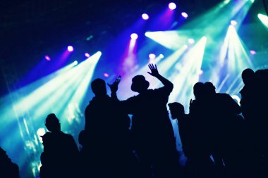 Parlak sahne ışıklarının önündeki bir konserde el silueti.