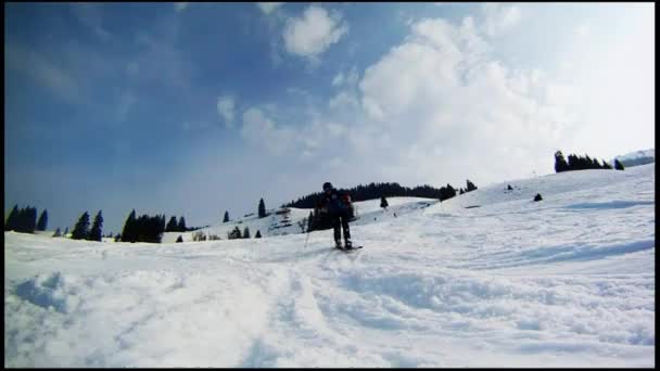 Movimiento lento de un esquiador esquiando por la ladera — Vídeo de stock