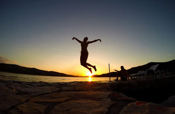 Silhueta de uma menina pulando ao pôr do sol na praia — Fotografia de Stock