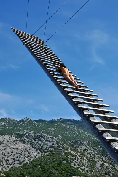 Sexy woman sunbathing on a wooden ladder — Stock Photo, Image