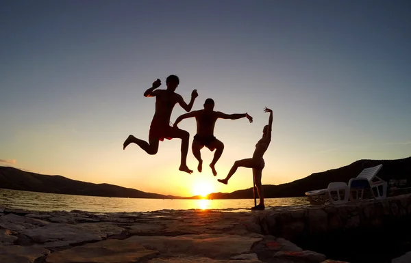 Silhouette of friends jumping at sunset on the beach