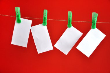 Kırmızı backgrou önünde ip üzerinde asılı boş notlar kısaltıldı