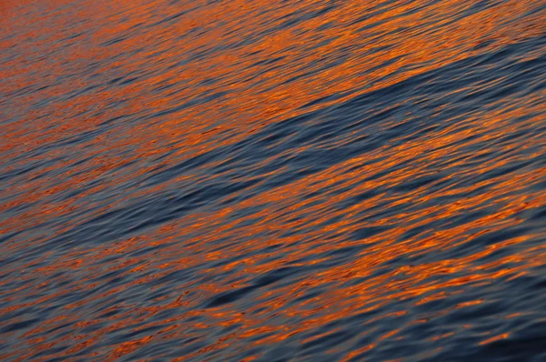 Orange Farbe glänzende Wasseroberfläche bei Sonnenuntergang — Stockfoto