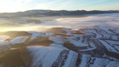 Gün batımında karlı kış tepelerinde uçarken hava manzarası