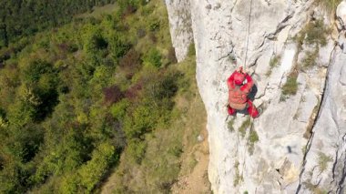 Bir dağ kurtarıcısının yanında uçmak kayalık bir duvarda İHA ile iple süzülmek