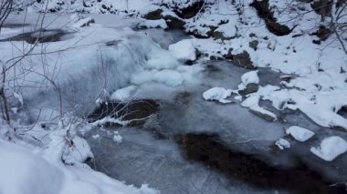 Kış mevsiminde aşırı soğuk havada dağ ormanlarında buzun altında akan su akıntısı