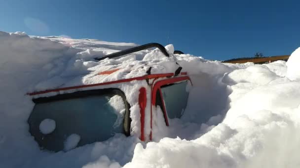 Зимой покрытая снегом машина. Снег похоронен автомобиль после снежной бури в горах — стоковое видео