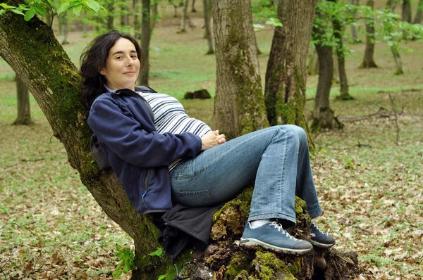 Pregnant woman relaxing on a tree trunk — Stock Photo, Image